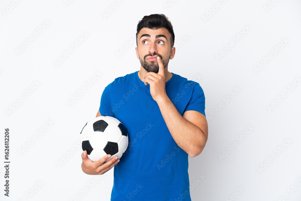 Handsome young football player man over isolated wall having doubts while looking up Handsome young football player man over isolated wall having doubts while looking up