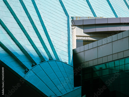 Abstract close-up of modern architectural structure with teal metal panels and sharp geometric lines, showcasing futuristic urban design and construction elements.