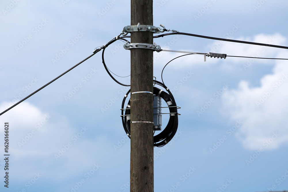 Ταπετσαρία A utility pole with a mounted fiber optic splice enclosure and a coiled drop cab