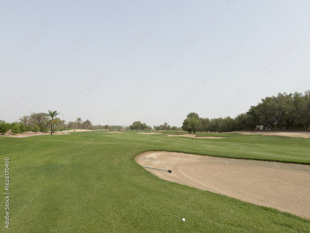 Manicured fairways and palm-lined greens of Abu Dhabi Golf Club on a bright, sunny day, showcasing the serene desert oasis setting Manicured fairways and palm-lined greens of Abu Dhabi Golf Club on a bright, sunny day, showcasing the serene desert oasis setting