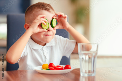 Creative boy playing with vegetables while eating