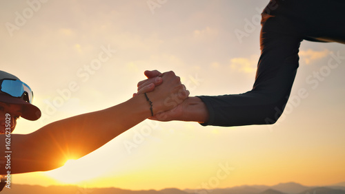 Two athletes, one in a cap and sunglasses, celebrate a cross-country victory at sunset. They clasp hands, symbolizing achievement, endurance, and mutual support in sport.