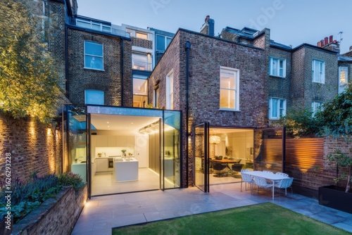 Modern glass extension and backyard of a stylish urban home in London during twilight, showcasing contemporary design and open living spaces