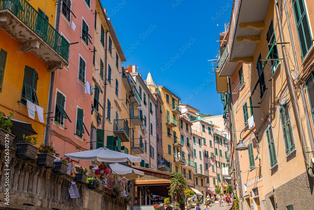 Fototapeta premium A photo of a narrow street with a few buildings and people walking