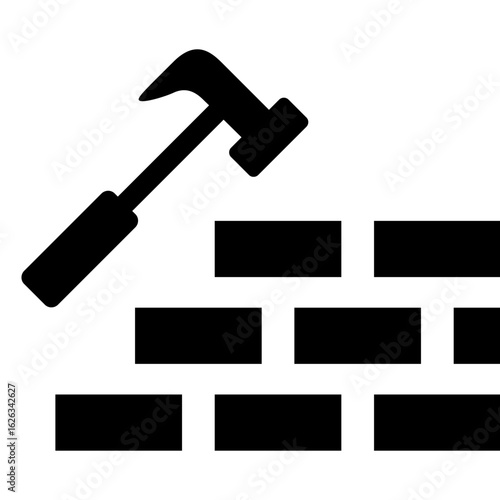 Construction worker using hammer to build brick wall at a job site during daylight hours in a busy urban area