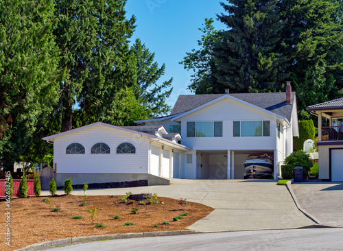 Suburban family house with small boat on trailer parked under carport