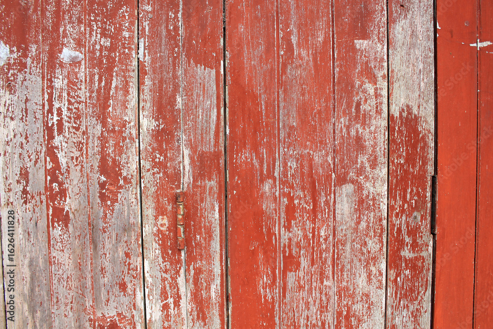 Naklejka premium Weathered Red Wooden Wall. A vintage red wooden wall with peeling paint and visible texture, ideal for rustic or antique themes.