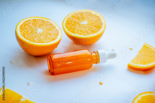 Vitamin C skincare concept with a glass bottle of organic facial serum and fresh orange slices arranged on a clean white background. A minimal, natural setup highlighting citrus-based beauty treatment