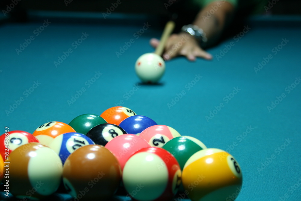 Skillful player lines up shot in vibrant pool hall during evening match with well-arranged billiard balls Skillful player lines up shot in vibrant pool hall during evening match with well-arranged billiard balls
