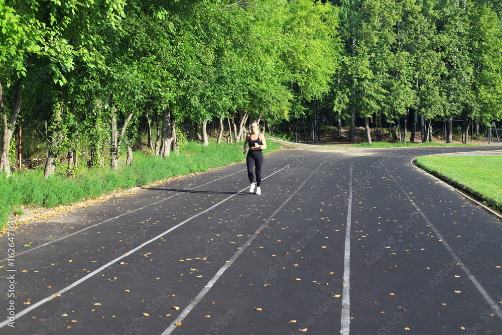 Adult European Woman in Black Running in Open Stadium. Adult European Woman in Black Running in Open Stadium.