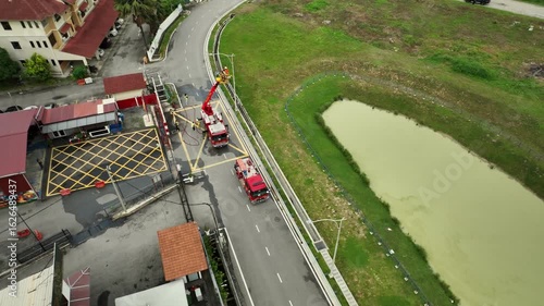 Aerial View of Firefighting Equipment at a Fire Station Parking Area Next to a Water Body