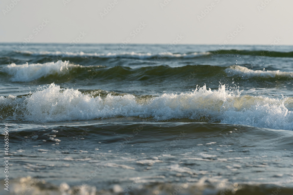 Fototapeta premium Sea waves splashing lit by sun, dramatic photo. Realistic photo, high resolution, water background