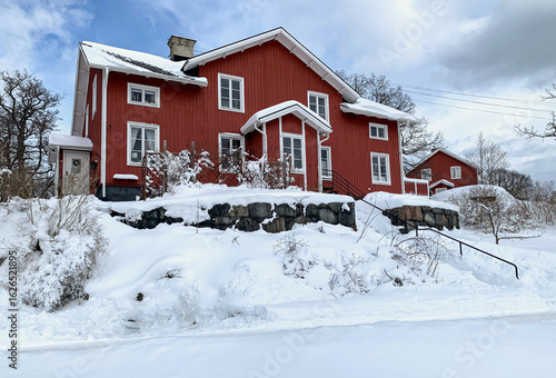 Red wooden two-story house on a snowy March day