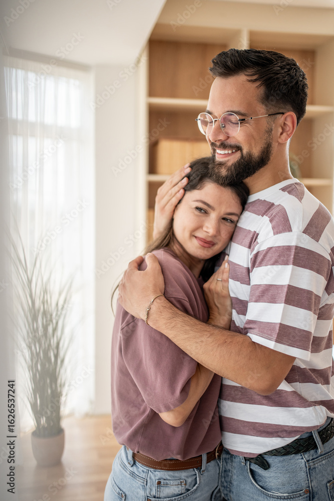 Happy couple embracing tenderly in modern apartment Happy couple embracing tenderly in modern apartment