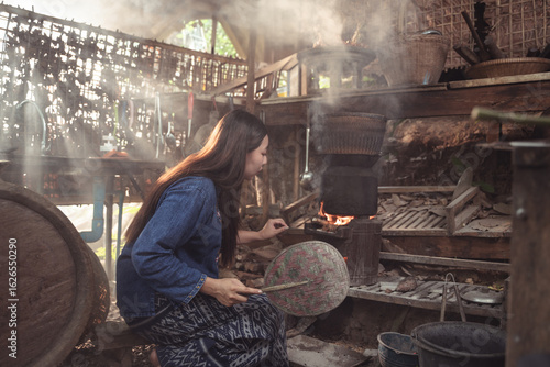 Beautiful sun rays filter through the smoke-filled air of a rustic kitchen, where a woman is preparing a meal. This atmospheric shot captures the timeless, cinematic beauty of traditional life.