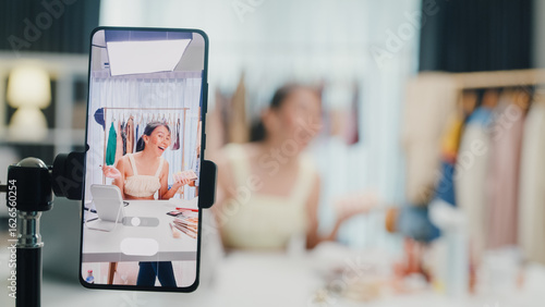 Fotografie Close-up phone screen recording Asia lady vlogger look phone camera apply eye shadow palette on skin live sale online screen in IG story reel tiktok work at home studio