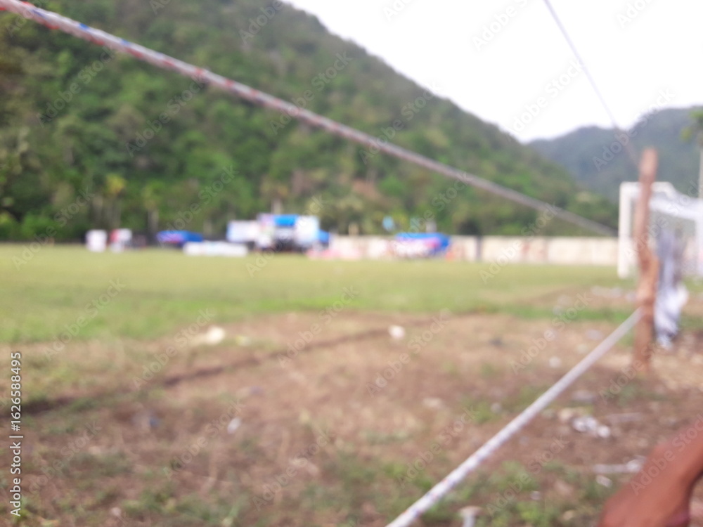 Obraz premium A blurry photo of a soccer field in the afternoon with people playing soccer in a soccer tournament. The bustling, lively atmosphere creates a sense of movement and energy.