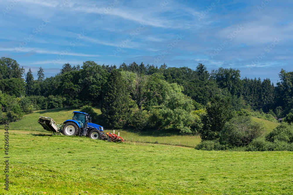 Blue agricultural tractor working in the acre fields to harvest the cereals Blue agricultural tractor working in the acre fields to harvest the cereals