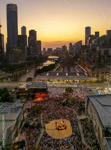 Aerial view of a crowd gathered around a vehicle in Federation Square, with the Yarra River winding through the city under a golden sunset, Melbourne, Victoria, Australia.
