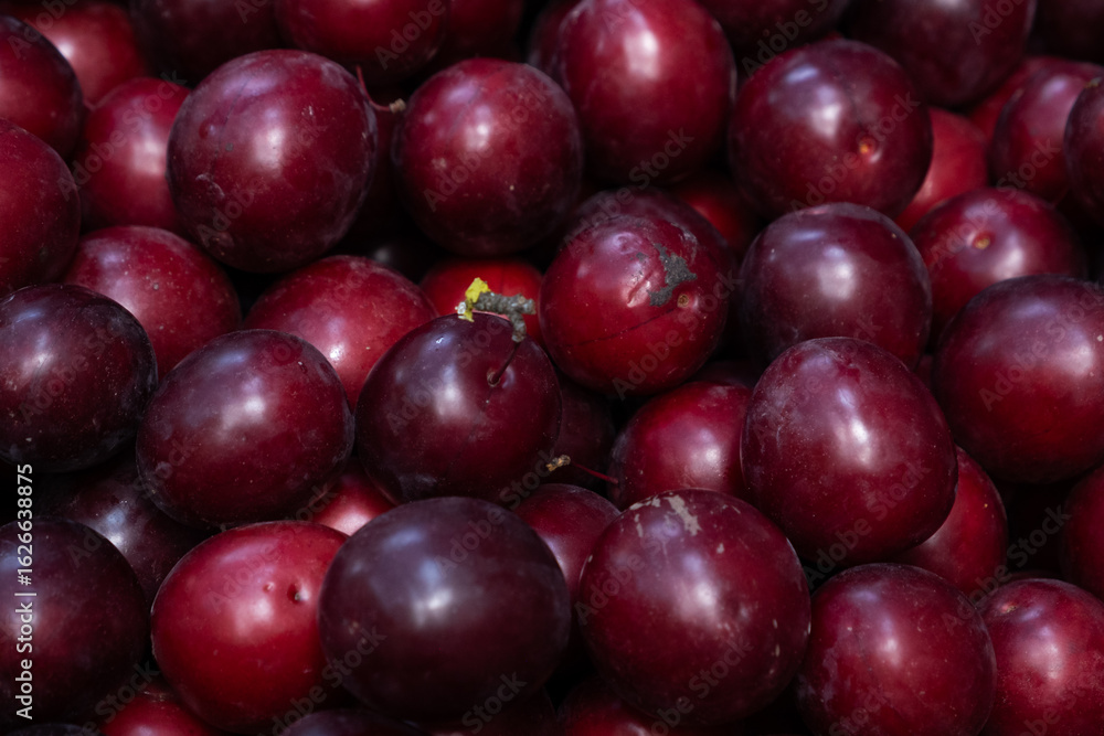 Macro photo of fresh ripe red plums. Glossy skin and natural imperfections highlight seasonal, organic stone fruits ideal for food, health, and harvest themes. Macro photo of fresh ripe red plums. Glossy skin and natural imperfections highlight seasonal, organic stone fruits ideal for food, health, and harvest themes.