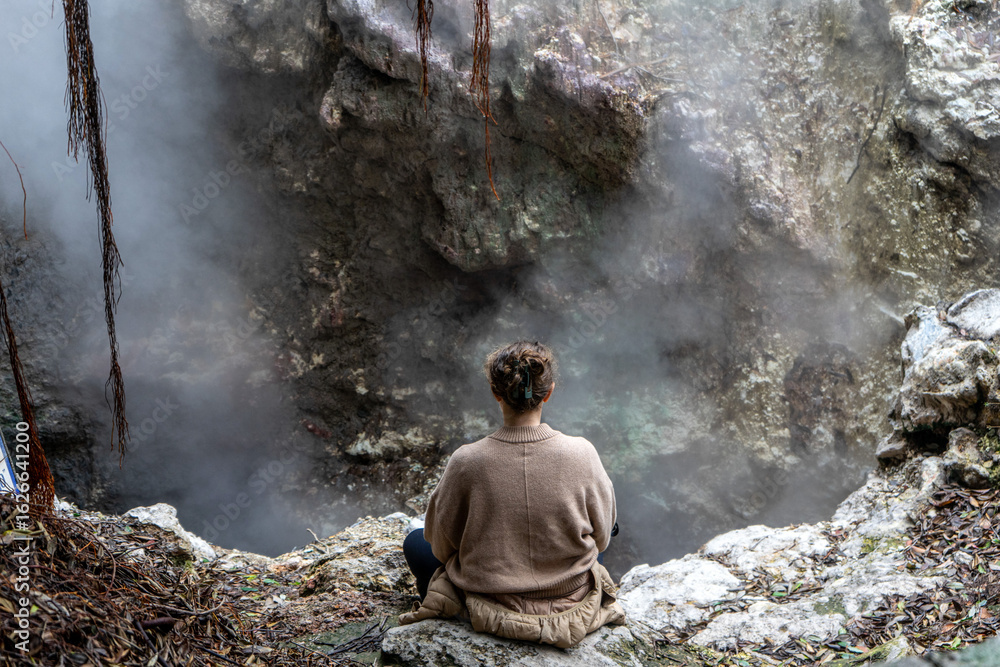 Obraz premium Woman meditating peacefully by geothermal hot springs at Furnas, São Miguel Island, Azores. Serenity, nature, wellness, and volcanic landscape in harmony.