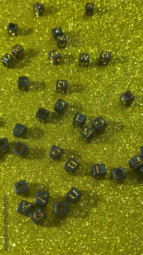Black cubes with letters on a shiny golden sequin	