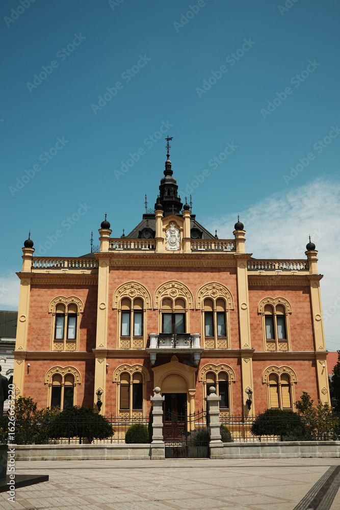 Naklejka premium The Bishops Palace in Novi Sad, Serbia. An ornate building with intricate details and a central tower, photographed on a sunny summer day.