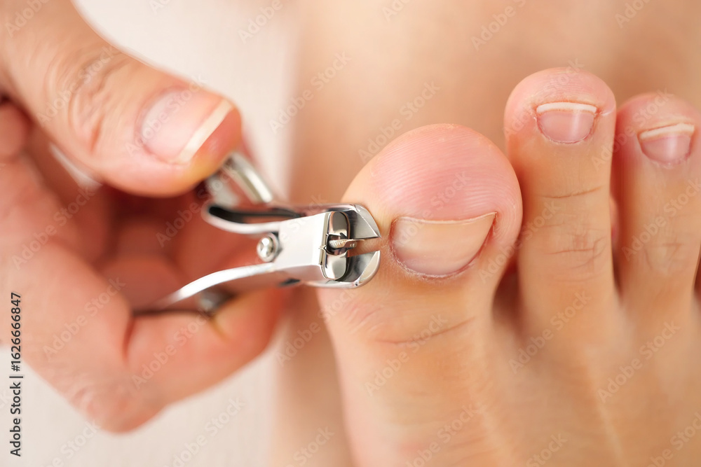 Fototapeta premium Close up of person using nail clippers to trim toenails fingernails clipping