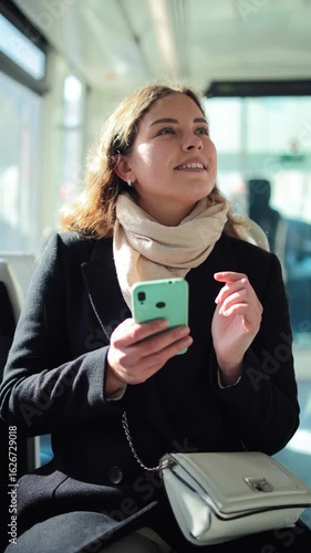 Happy female passenger engaged with her smartphone, exploring different apps and browsing the internet while traveling on public transport, embodying the essence of digital connectivity and