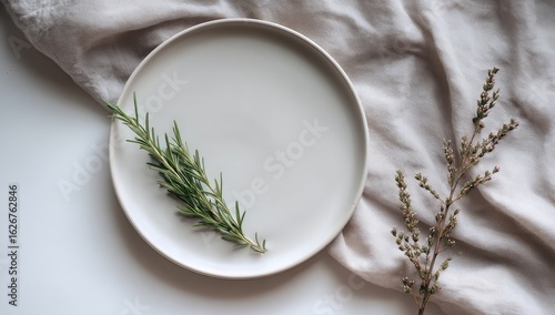 Pale plate with rosemary sprig, on cloth