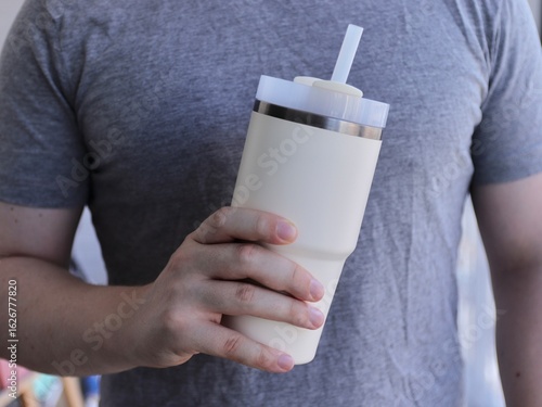 Man Holding Reusable Insulated Tumbler with Straw in Casual Setting