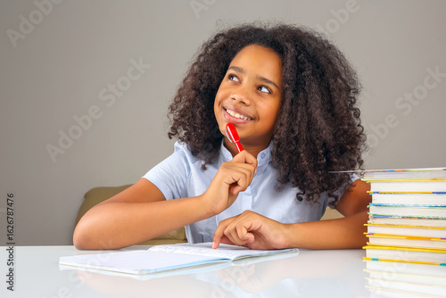 Young girl engaged in creative writing with notebook and books at home