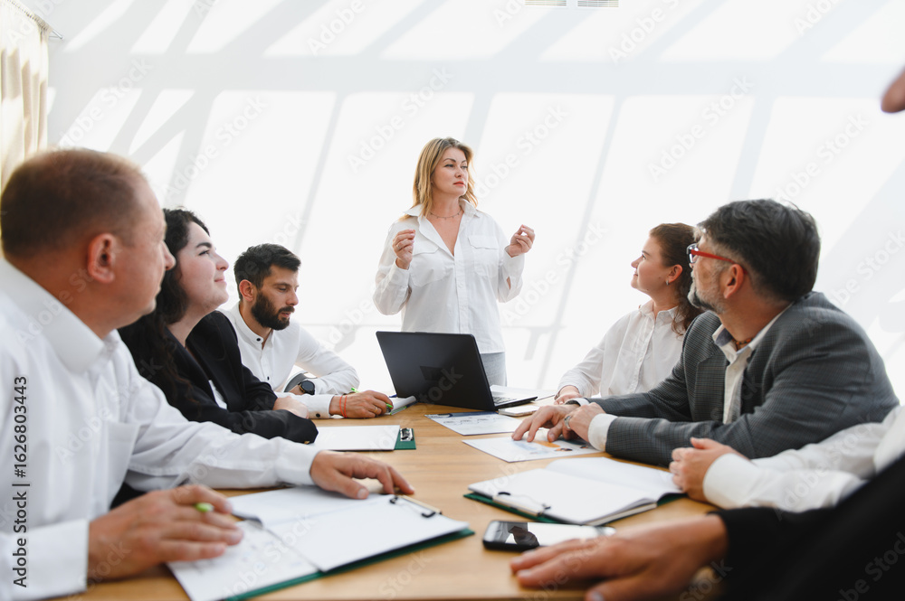 Business team meeting, female leader inspiring her colleagues during a corporate presentation Business team meeting, female leader inspiring her colleagues during a corporate presentation