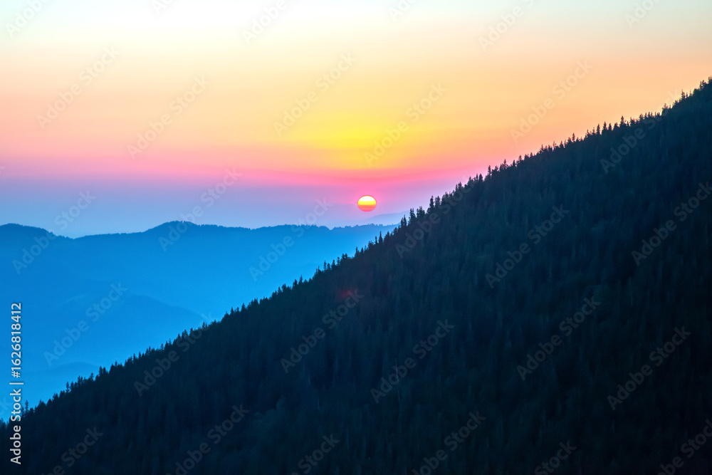 Fototapeta premium Sunset over the mountains with vibrant colors in the sky at dusk