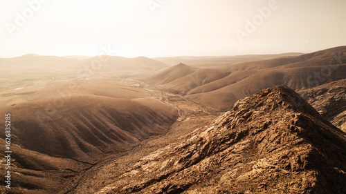 Obraz na płótnie Aerial view of a vast, dry mountain landscape on Fuerteventura bathed in warm evening light