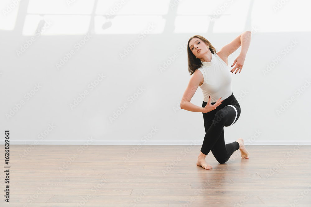 Fototapeta premium Young talented woman dancing modern choreography in dance school studio