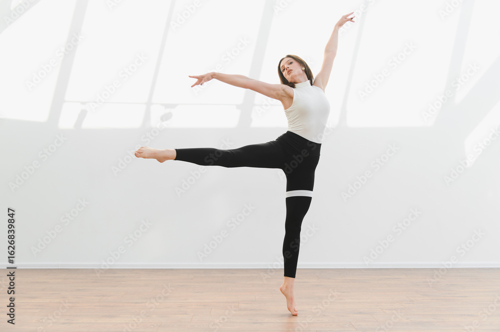 Fototapeta premium Young talented woman dancing modern ballet in a studio with natural light