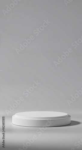A white circular podium or product stand on a gray background, with soft shadows and empty space above for product placement.