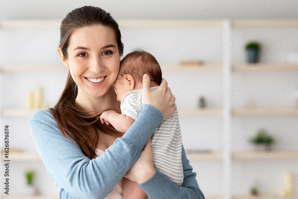 Fototapeta premium Happy Maternity Time. Portrait Of Beautiful Young Mother Embracing Adorable Newborn Child And Smiling At Camera, Happy Millennial Woman Bonding With Her Little Infant Baby At Home, Copy Space