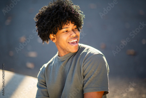 Joyful young mixed race man laughing in casual outfit outdoors