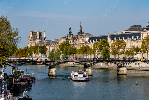 Scenic river cruise on the Seine, showcasing a tour boat, historic bridges, and the iconic Louvre Museum.