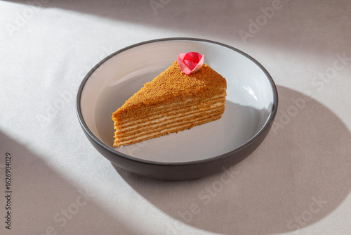 Fotografie Traditional honey layered cake with soft cream and golden crumbs served with an
