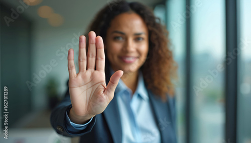 Businesswoman holds hand up in stop gesture to reject sexual harassment, violence. Female pro opposes bullying, abuse in workplace. Represents safety, self-protection, resistance against unlawful