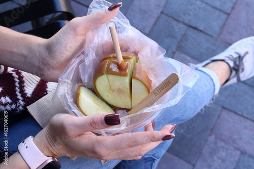 Woman Holding a Caramel Apple in Hand