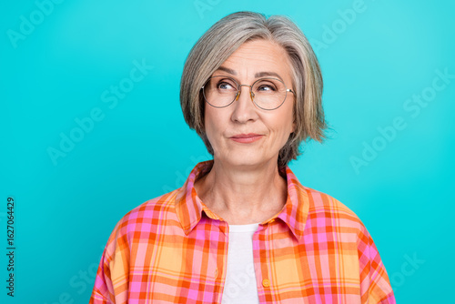 Фотография Charming elderly woman with a vibrant checkered shirt against a turquoise backdr