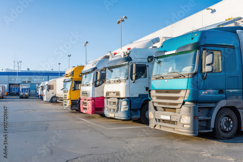 Wallpaper Mural Row of colorful large trucks parked in industrial area under clear blue sky, showing transportation and logistics vehicles Torontodigital.ca