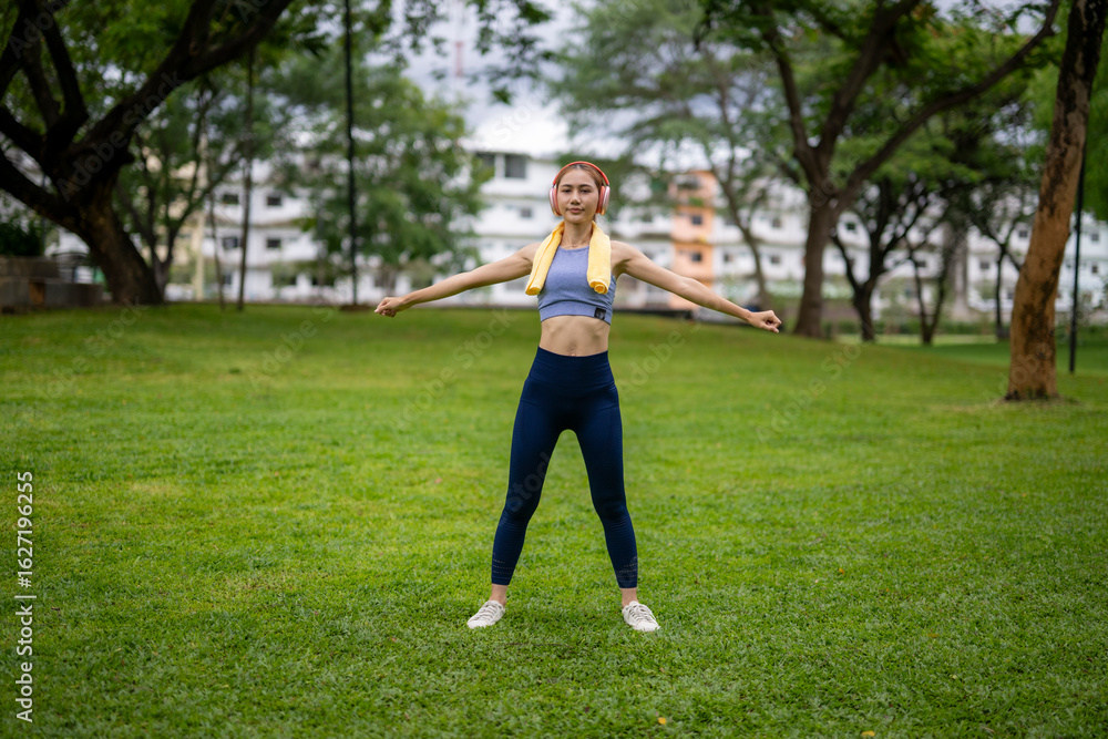 A woman is standing in a park, wearing a yellow towel and doing a push up A woman is standing in a park, wearing a yellow towel and doing a push up