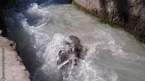 Fast flow of water from a mountain river through a concrete channel