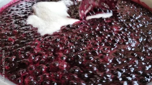 The process of making homemade blackcurrant jam. Add sugar when cooking the berries