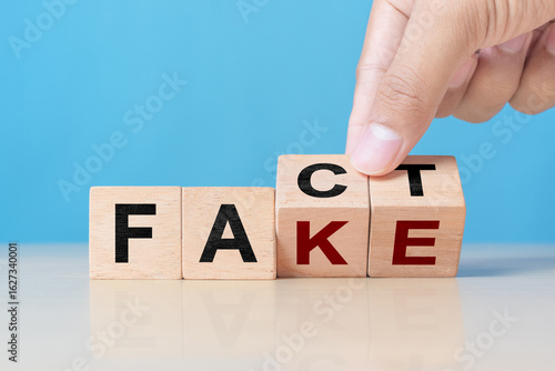 Foto Business man hand holding wooden cube with flip over block FAKE to FACT